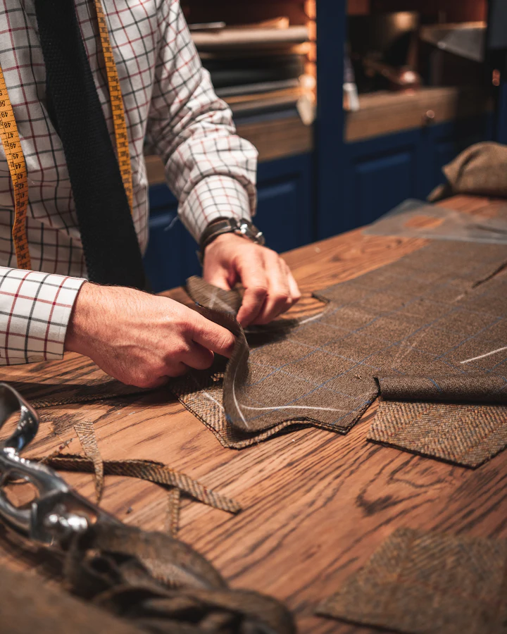 Tailor cutting tweed fabric on a wooden workbench